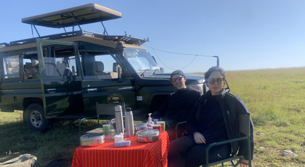 Two guests enjoy a breakfast picnic while on a game drive in the Masai Mara.