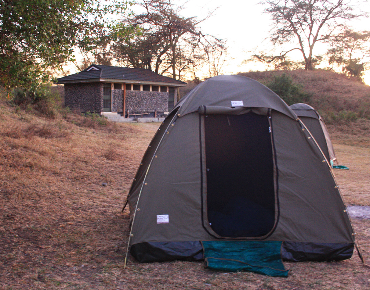 A guest tent and sanitary block in the background on a public campsite in Kenya