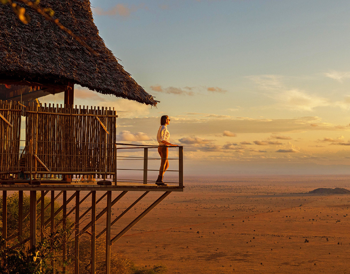 Woman standing on balcony at Lions Bluff Lodge overlooking Lumo Conservancy