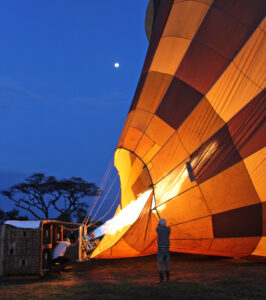 The burner of a hot air balloon is filling the balloon early in the morning while the sky is still dark.