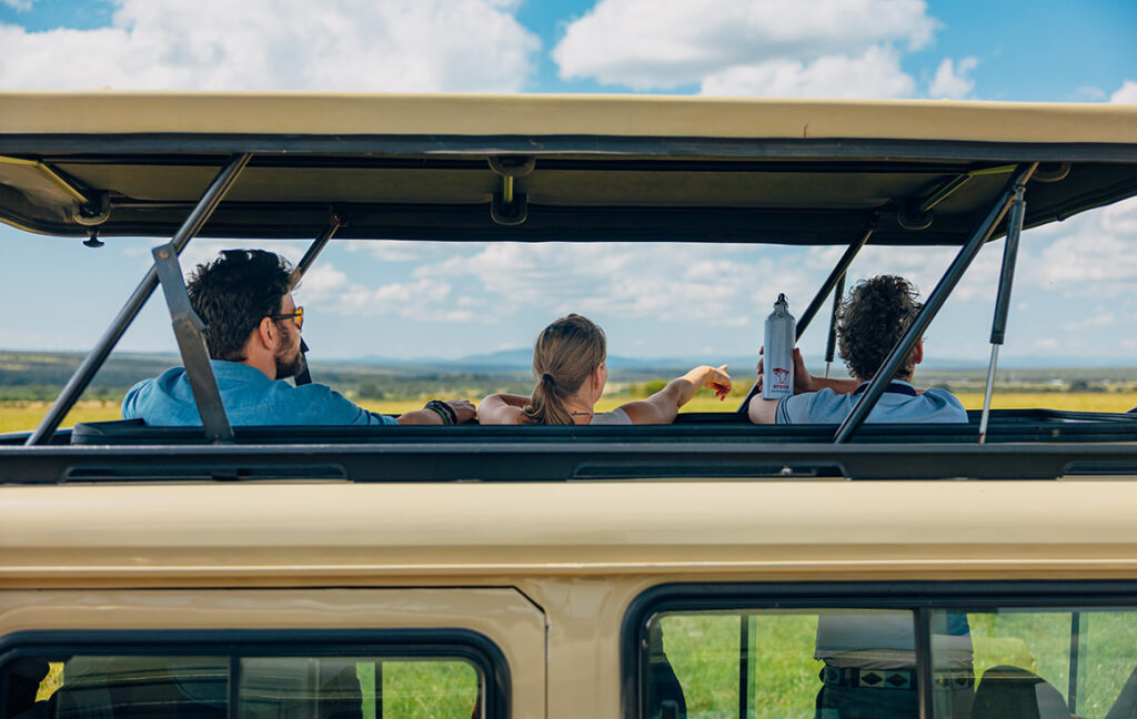 A group of travellers looking out of the pop-up roof while on safari in Kenya.