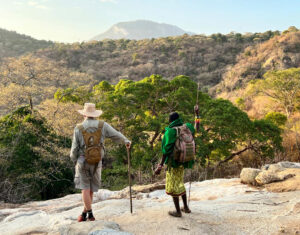 A guide and guest standing on a hill, overlooking the landscape while on a walking safari in Kenya.