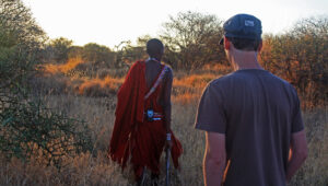 Guide and guest walking through a bushy area.