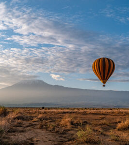 Views of Mt Kilimanjaro with a striped balloon floating past at morning light.
