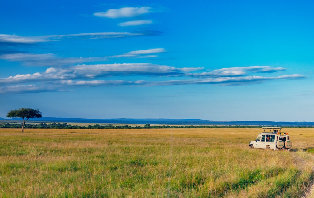 A game drive vehicle drives through the savanna of the Maasai Mara on a private Kenya safari.