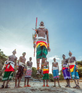 A Samburu man jumps very high while the others look on.