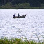 Two people sit in a small boat on Lake Victoria, on the Tanzanian side of the lake.