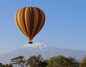 A striped balloon in front of Mt Kilimanjaro, the sky is blue.