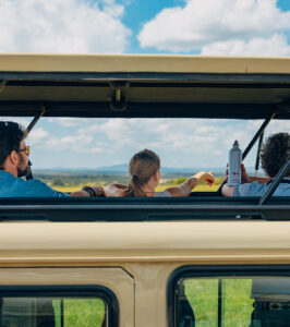 A small group of travellers looking out of a pop-up roof in a safari vehicle.