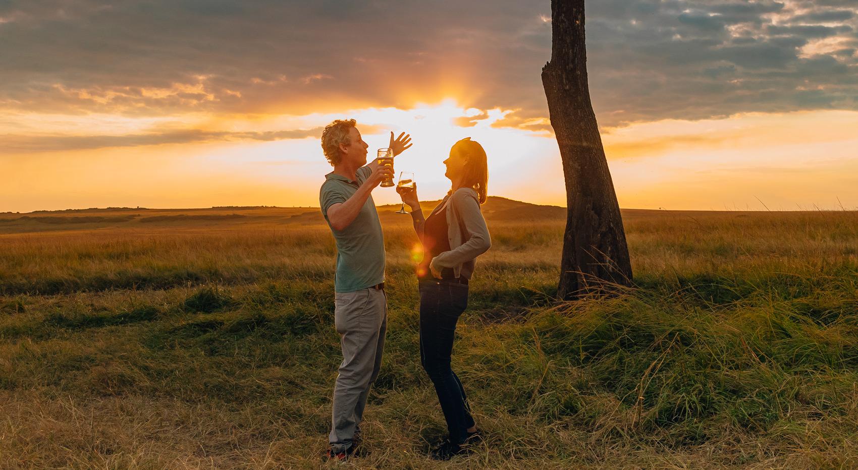 Guests in the Masai Mara enjoying sundowners, wearing casual safari clothes. Guests in the Masai Mara enjoying sundowners, wearing casual safari clothes.
