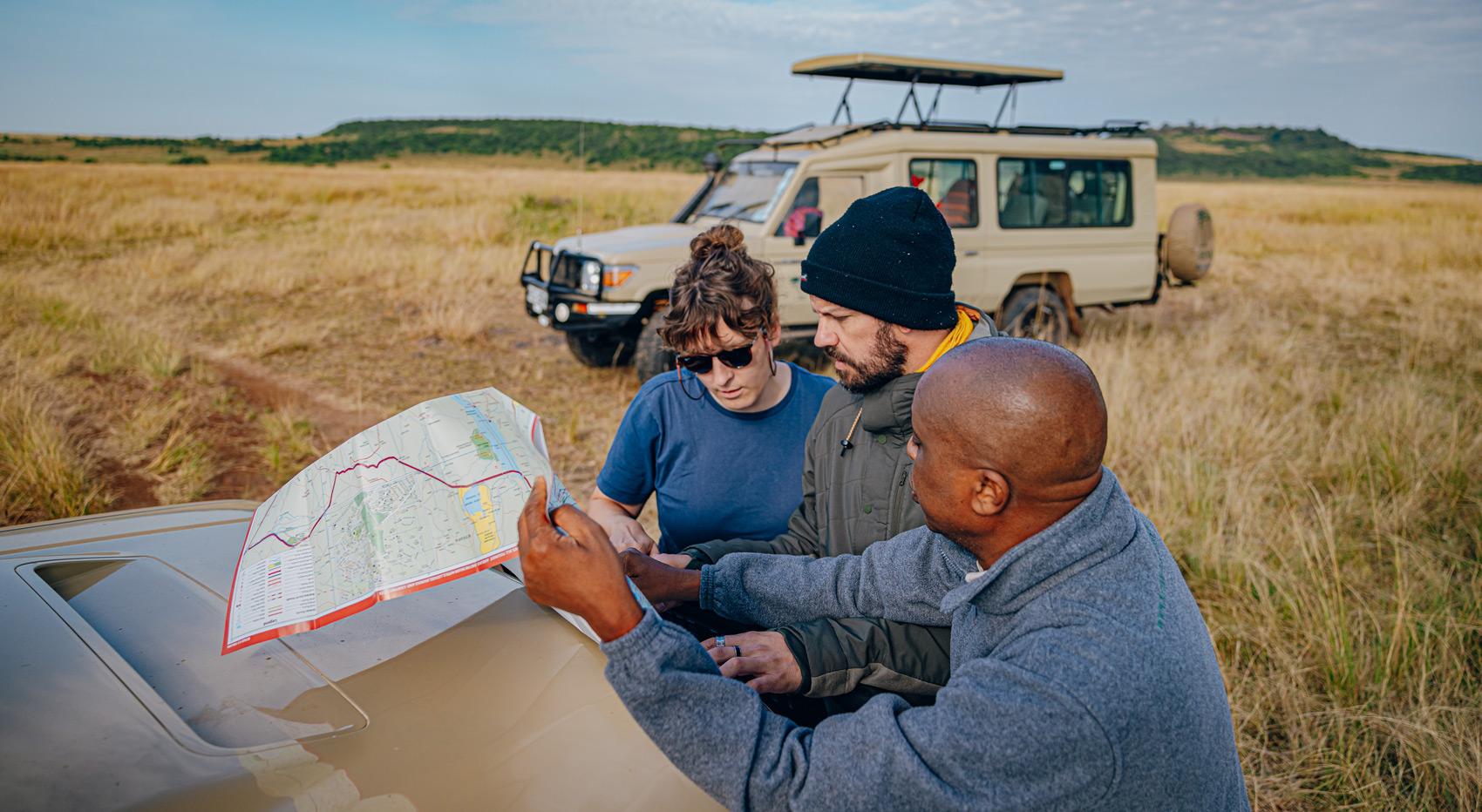 How to Book a Safari in Kenya. Guests with safari guide, looking at a map.