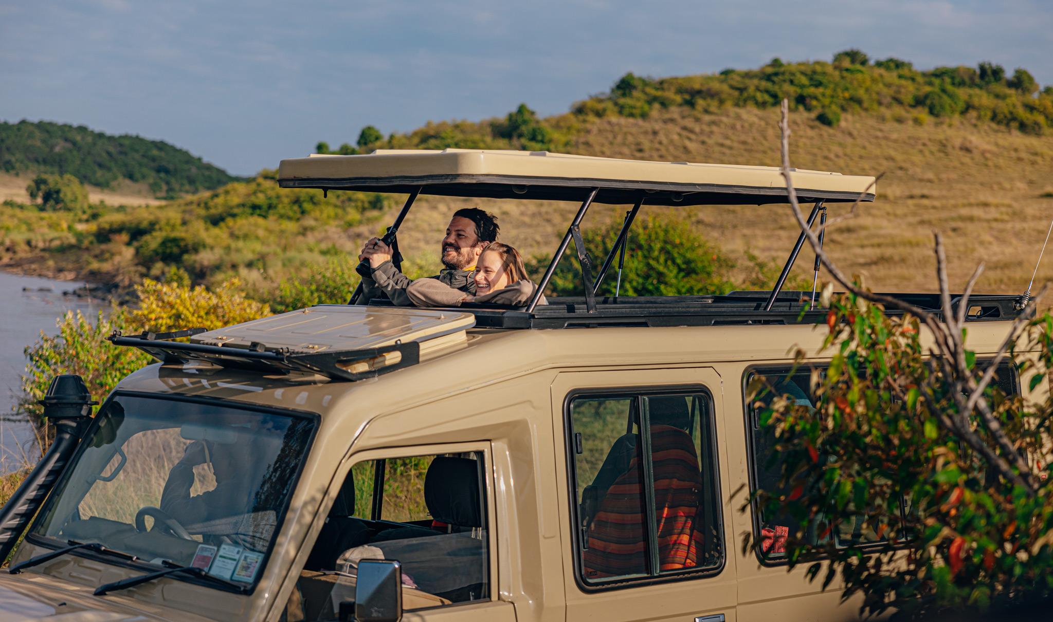 Guests on safari in the Masai Mara, looking out from the pop up roof.
