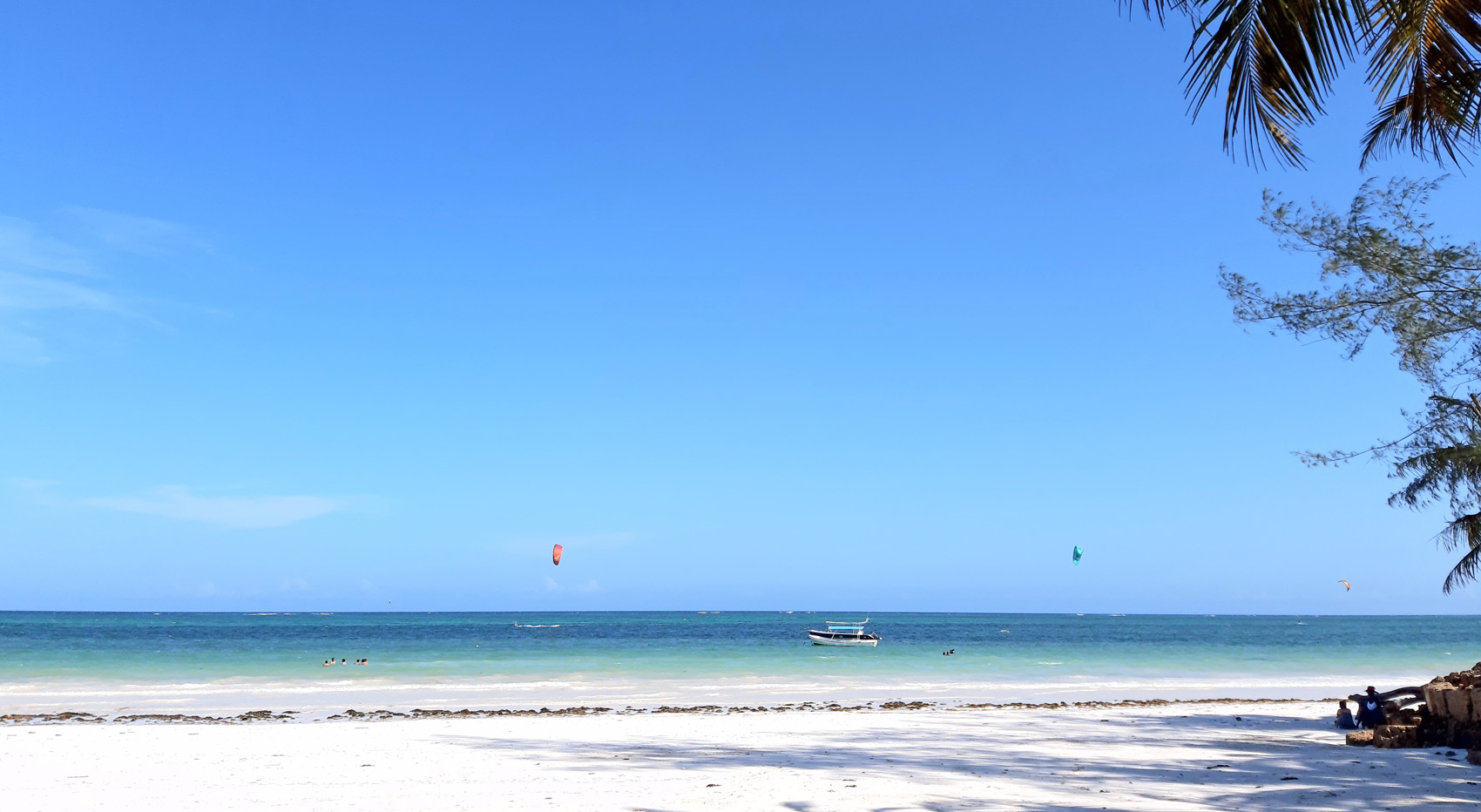 Kite surfers in the backgrownd enjoying themselves in the blue Indian Ocean at Dianis white sandy beach.