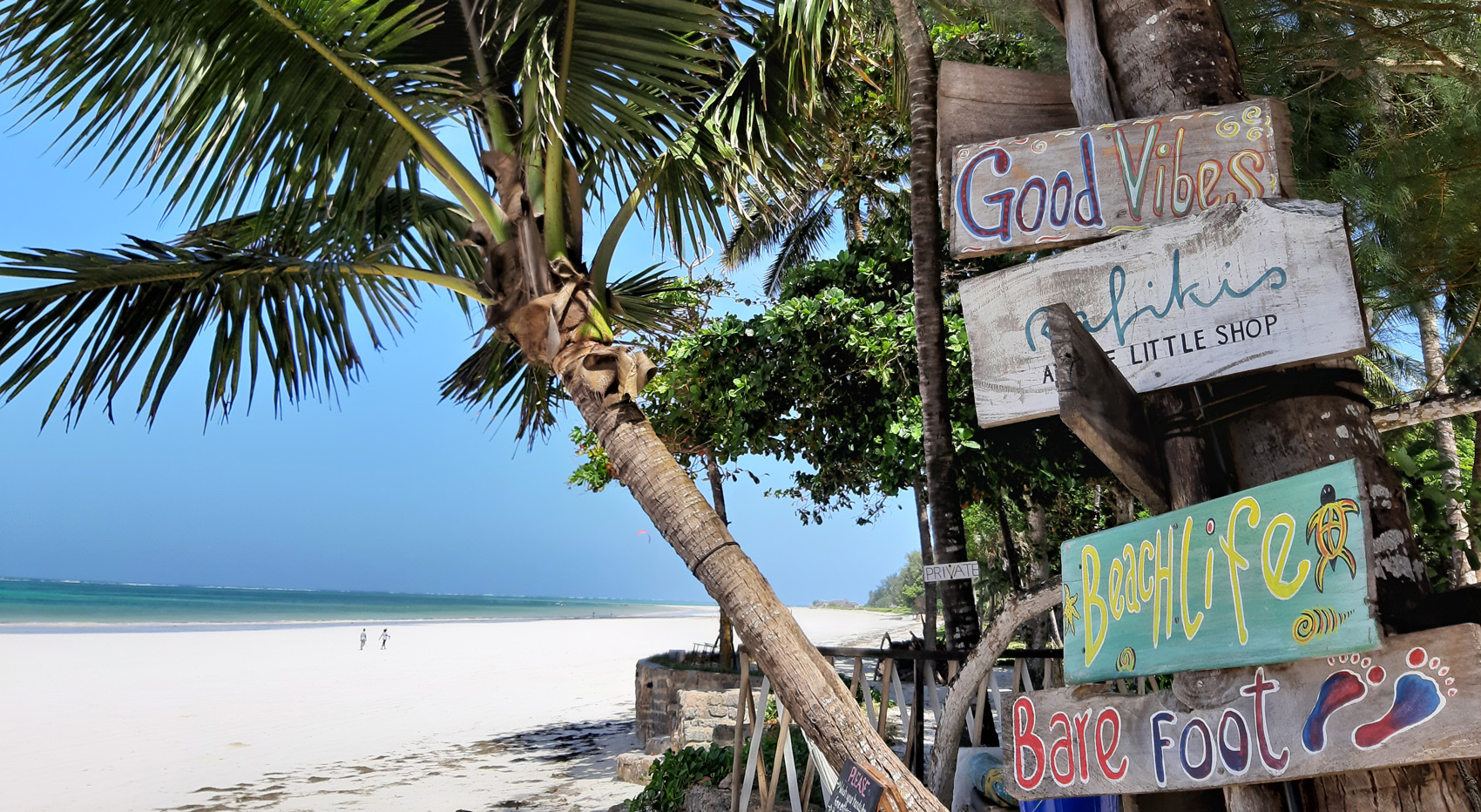 Diani beach set against driftwood signs at the entrance to Kenyaways.