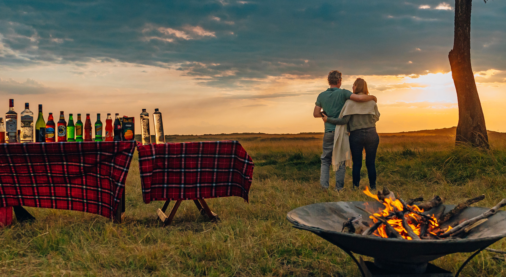 A couple enjoying the sunset and sundowers in the Masai Mara.