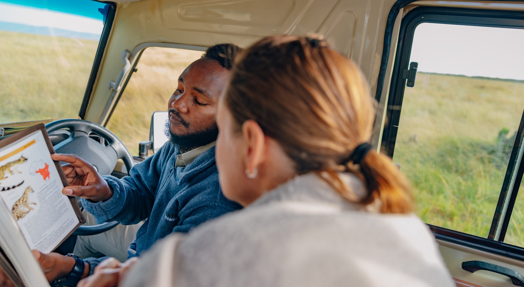 A guide showing a kenya safari solo traveller a reference book on wildlife. 