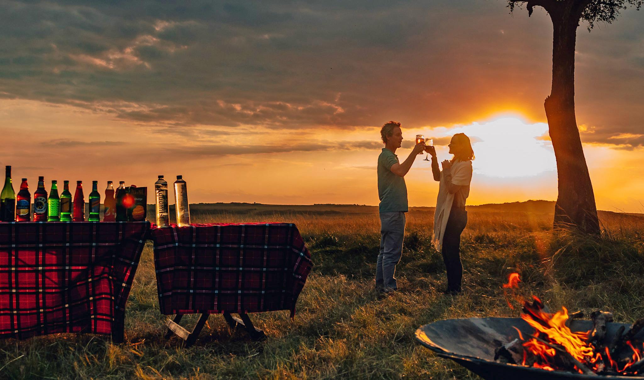 A couple toasting in the Masai Mara at sunset.