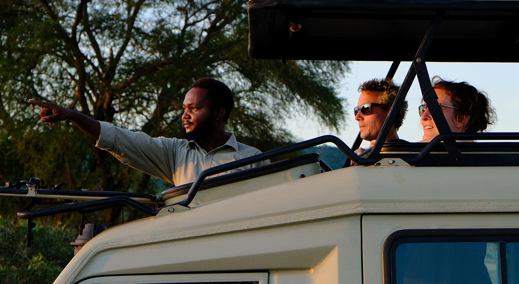 Guide and Team in a safari vehicle with open pop-up roof in Tsavo National Park.