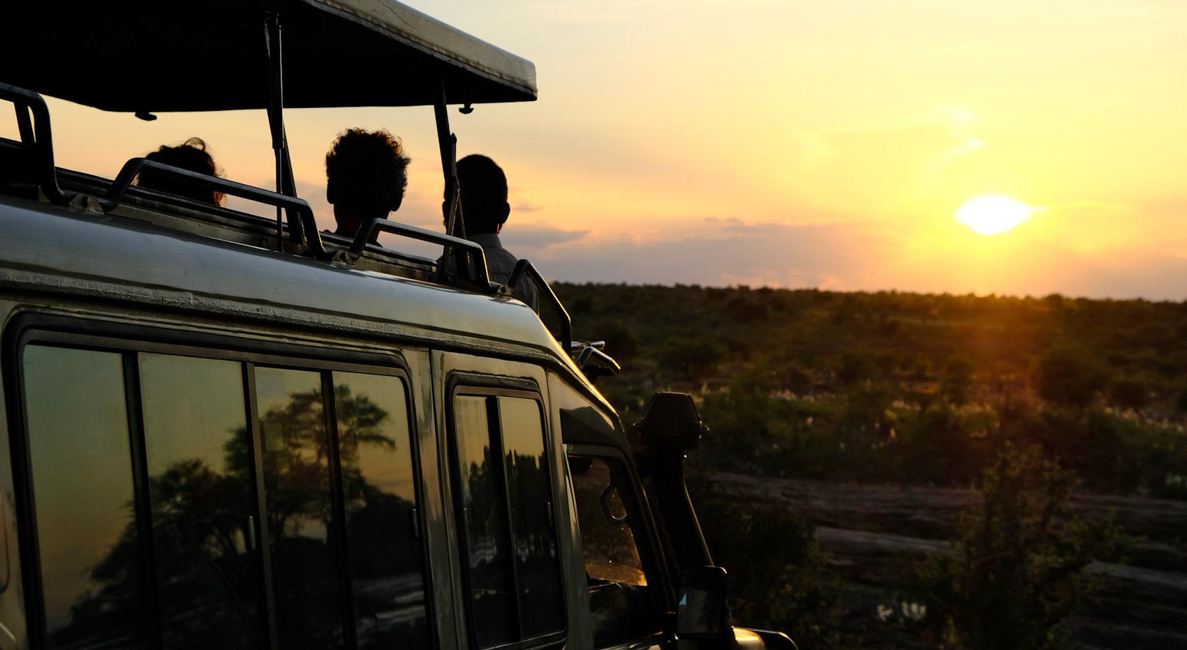 A safari vehicle in Tsavo East with guests watching the sunset. 
